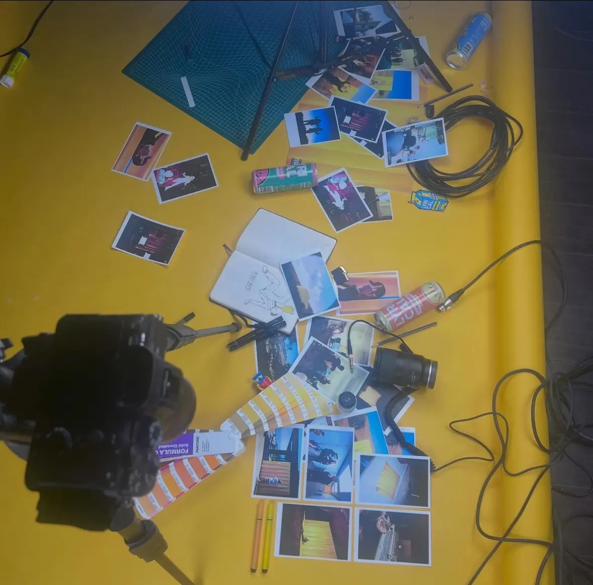 Creative flatlay — camera, photo prints, Pantone swatches on a yellow sweep.